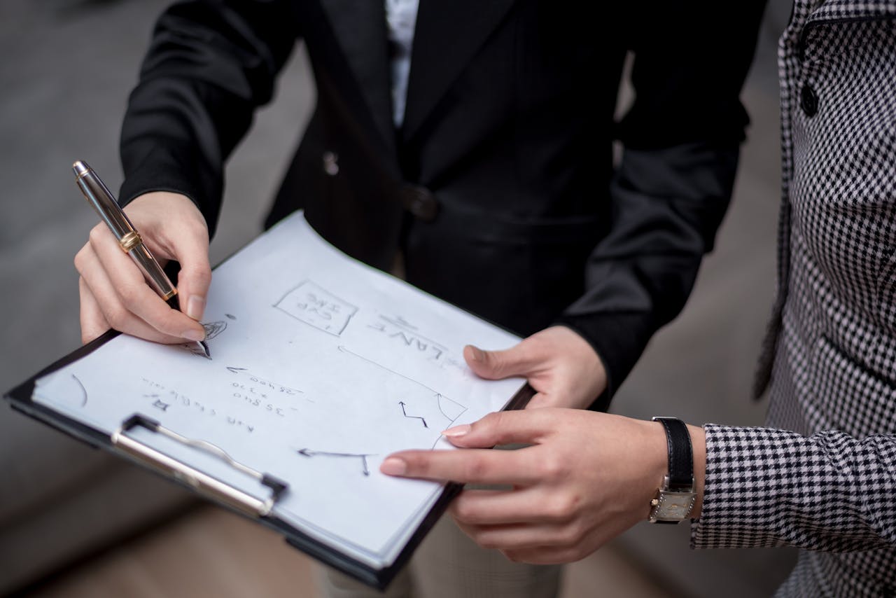 Close-up of professionals collaborating, taking notes on a clipboard.